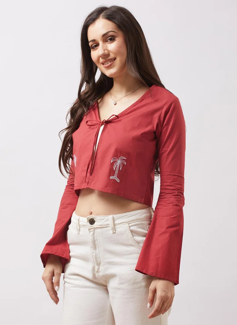 جلو باص بلوزة نسائية قصيرة مفتوحة من الأمام بأكمام واسعة وياقة على شكل حرف  ورباط وتفاصيل مطرزة باللون البني